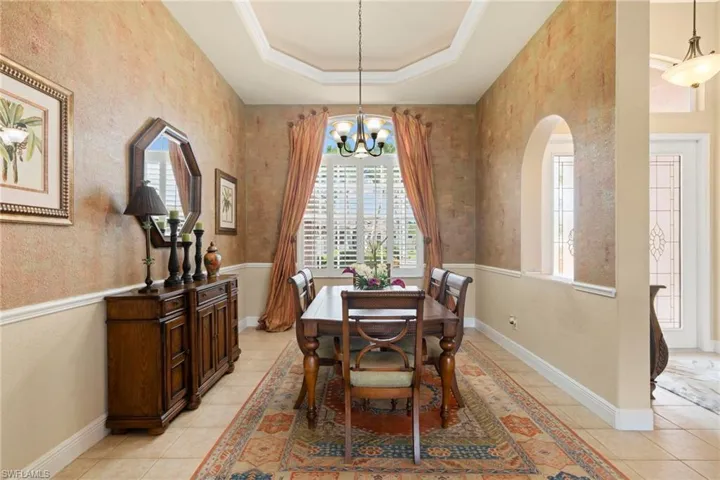 Dining area with 12' tray ceiling, custom made drapes and wall paint, Peruvian floor rug, Plantations shutters for oversized dining room windows.