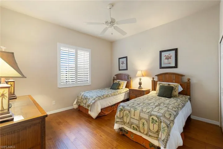 Guest Bedroom 2, all Tommy Bahama furniture and tv stay, featuring hardwood / wood-style flooring and a ceiling fan and double closets.