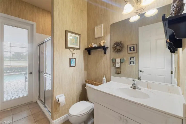 This Cabana Bathroom off the pool lanai area has a vanity, a shower stall, and tile patterned flooring.