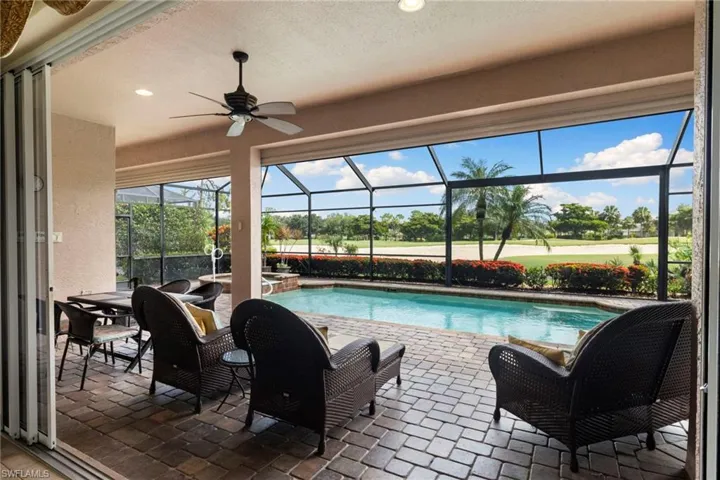 View of pool featuring a patio, golf course view, a lanai, ceiling fan, and a pool with connected hot tub, all outdoor furniture stays.