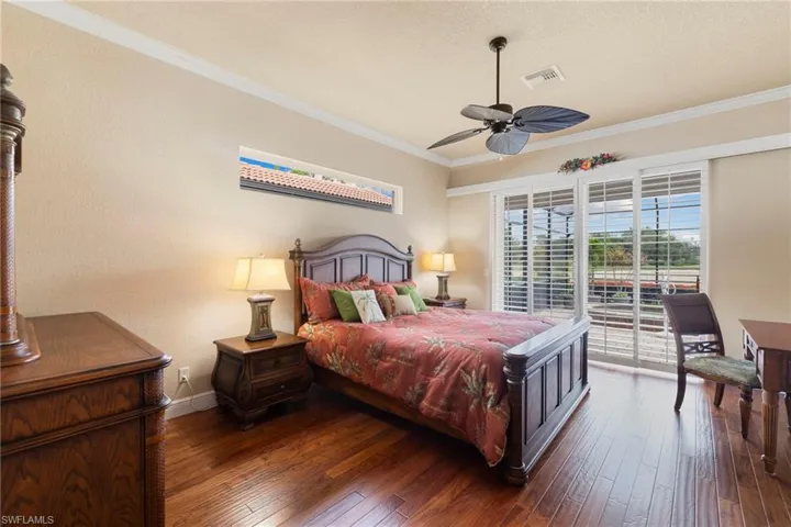 Master Bedroom #1 featuring access to pool and lanai, plantatoin shutters on the sliding glass doors, hard wood floors, and all Bedroom furniture stays, bed, dresser, tv armoire and desk with chair.