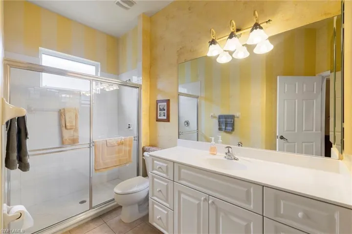 Bathroom 2, guest bathroom, featuring wallpapered walls, vanity, tile patterned floors, and a stall shower