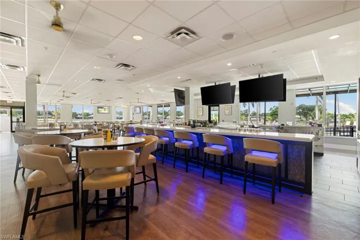 The Nest Dining room with wood finished floors and a paneled ceiling bar surrounded by TVs.