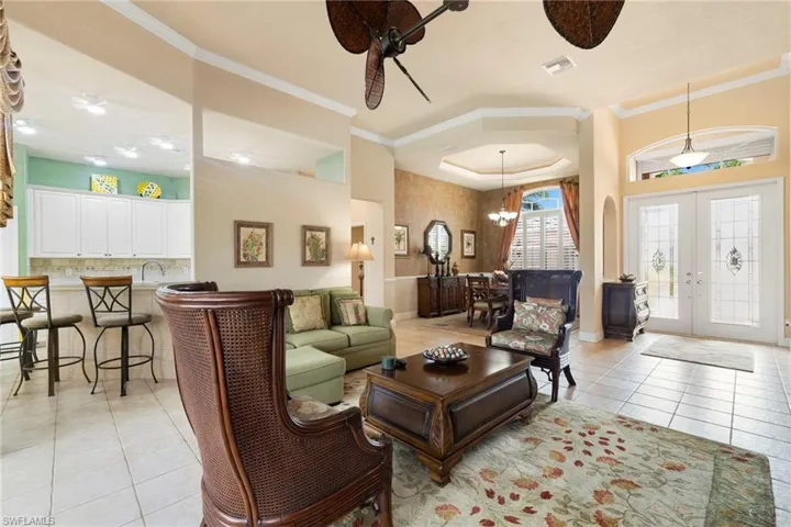 Living room with light tile patterned floors, crown molding, 8' french doors and a double ceiling fan from Rob and Stuckey's furniture store.
