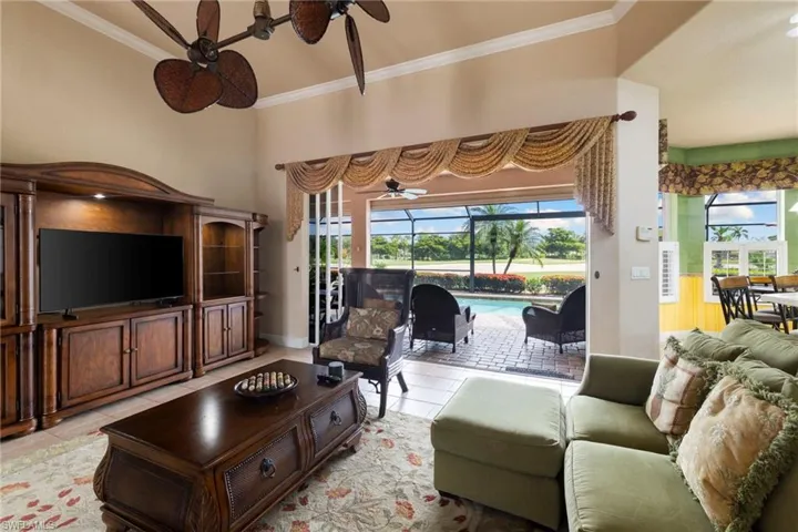 Living room featuring ceiling fan, light tile patterned flooring, crown molding, and plenty of natural light