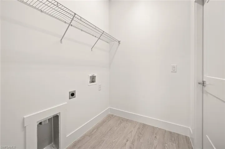 Washroom featuring electric dryer hookup, washer hookup, light wood-style floors, baseboards, and laundry area