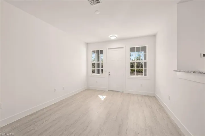 Empty room with light wood-type flooring, visible vents, and baseboards