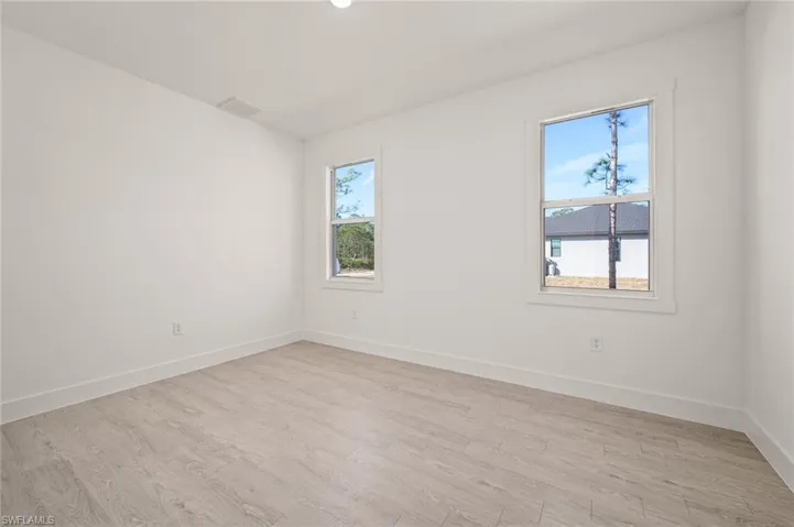 Spare room with light wood-style floors, visible vents, and baseboards