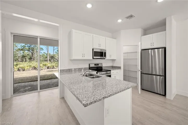 Kitchen with a sink, white cabinets, visible vents, and stainless steel appliances