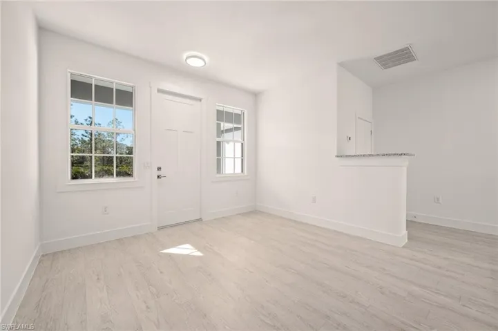 Foyer featuring visible vents, baseboards, light wood-style floors, and a healthy amount of sunlight