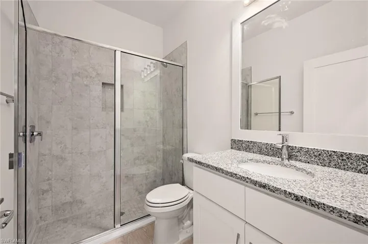 Full bathroom with a stall shower, toilet, and vanity