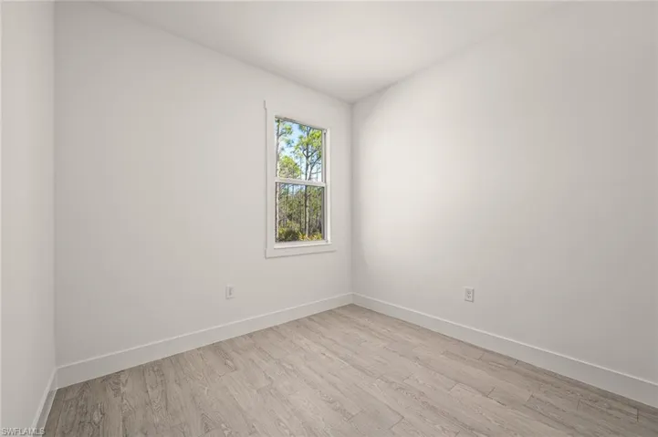 Spare room featuring light wood-style flooring and baseboards