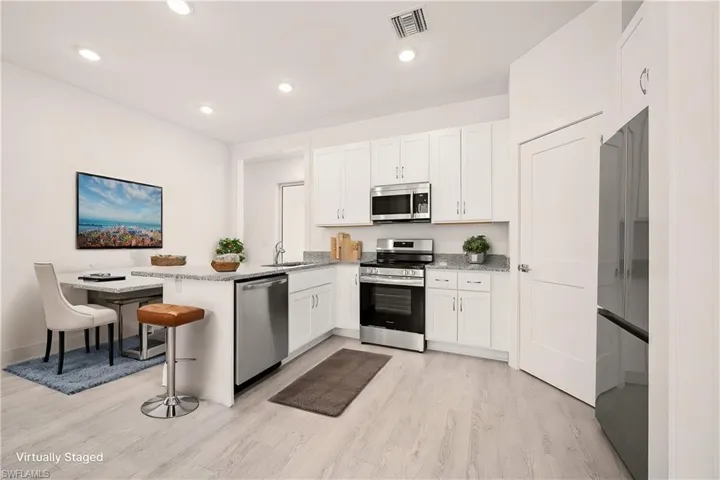 Kitchen featuring visible vents, white cabinetry, appliances with stainless steel finishes, a peninsula, and light wood finished floors