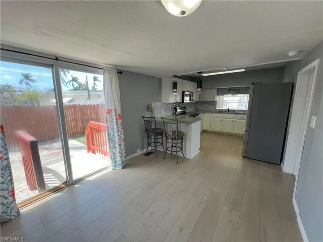 Kitchen featuring a peninsula, stainless steel appliances, white cabinetry, a sink, and light wood-type flooring