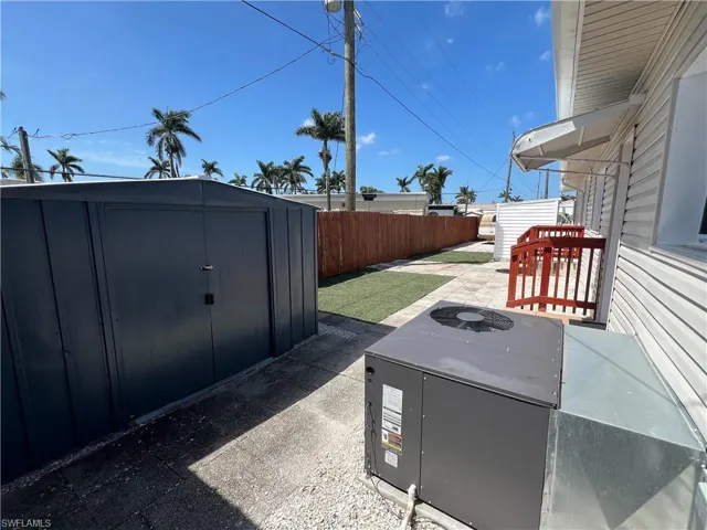 View of patio / terrace with cooling unit, an outbuilding, a fenced backyard, and a storage shed