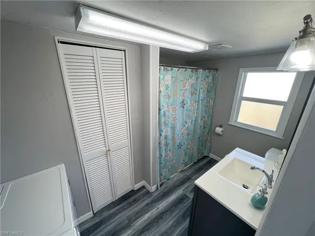 Bathroom 1 featuring a closet, baseboards, wood finished floors, and vanity