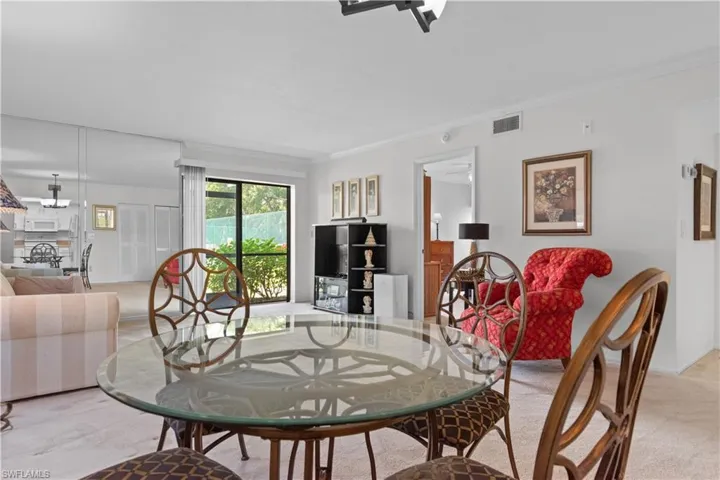 Carpeted living space with a glass-top dining table, a mirrored accent wall, and a sliding glass door