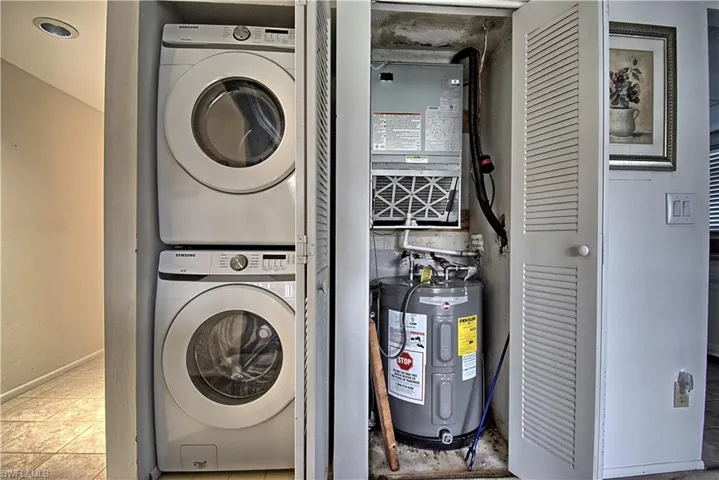 Dedicated laundry closet with stacked washer and dryer, adjacent to an HVAC system and water heater within a separate utility closet