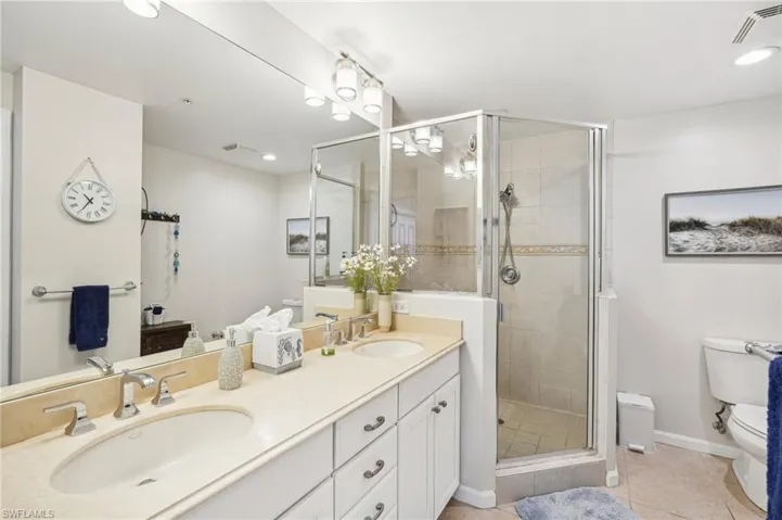 Bathroom with toilet, vanity, tile patterned floors, and a shower with door