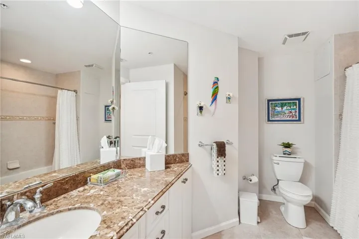 Bathroom featuring toilet, vanity, a shower with shower curtain, and tile patterned flooring