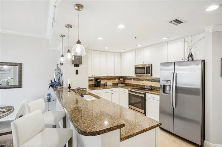 Kitchen featuring dark stone countertops, stainless steel appliances, sink, and pendant lighting