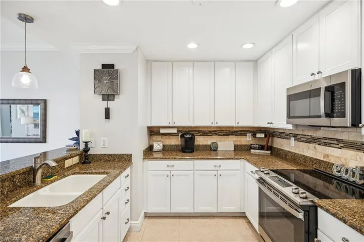 Kitchen featuring white cabinets, stainless steel appliances, and dark stone countertops