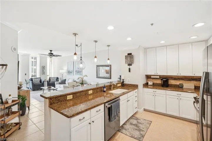 Kitchen featuring light tile patterned flooring, kitchen peninsula, white cabinetry, and stainless steel appliances