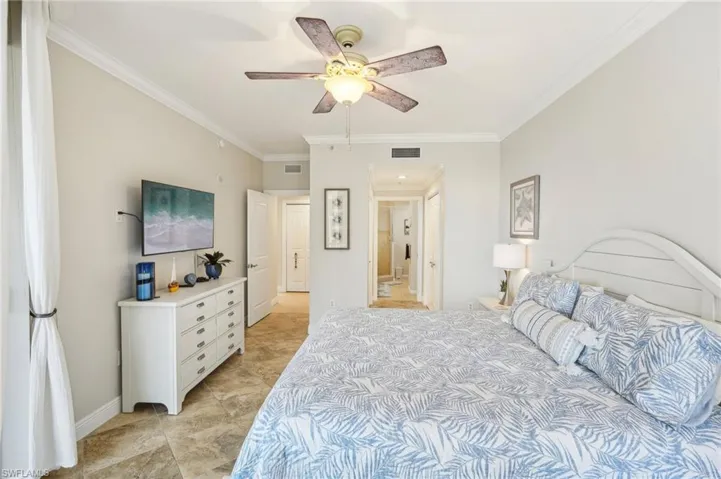 Bedroom with ceiling fan, crown molding, and ensuite bath