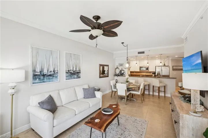 Tiled living room featuring ceiling fan and ornamental molding