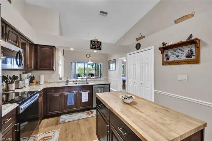 Kitchen with appliances with stainless steel finishes, light wood-type flooring, butcher block countertops, and sink