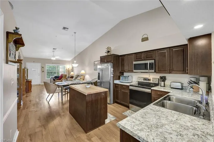 Kitchen with lofted ceiling, sink, a kitchen island, appliances with stainless steel finishes, and light hardwood / wood-style floors