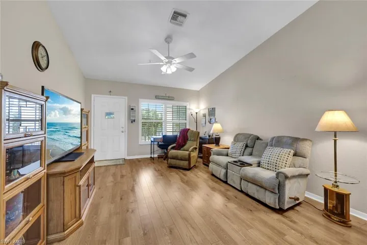Living room with ceiling fan, vaulted ceiling, and light wood-type flooring