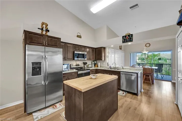 Kitchen featuring sink, a kitchen island, stainless steel appliances, and high vaulted ceiling