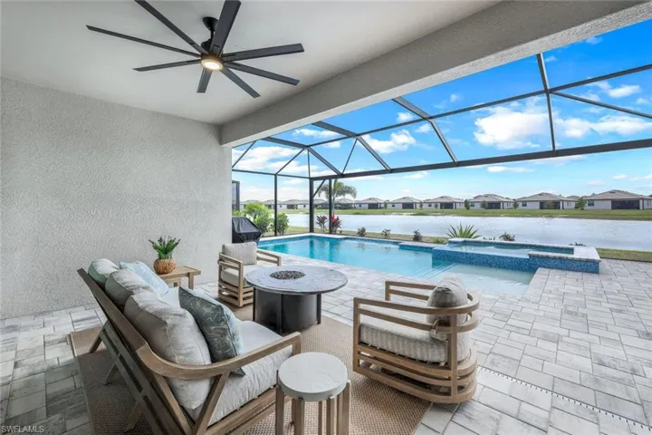 View of swimming pool featuring a lanai, an outdoor living space with a fire pit, a patio, and an in ground hot tub