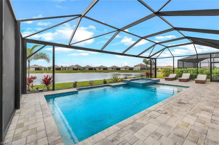 View of swimming pool featuring a water view, an in ground hot tub, a lanai, and a patio