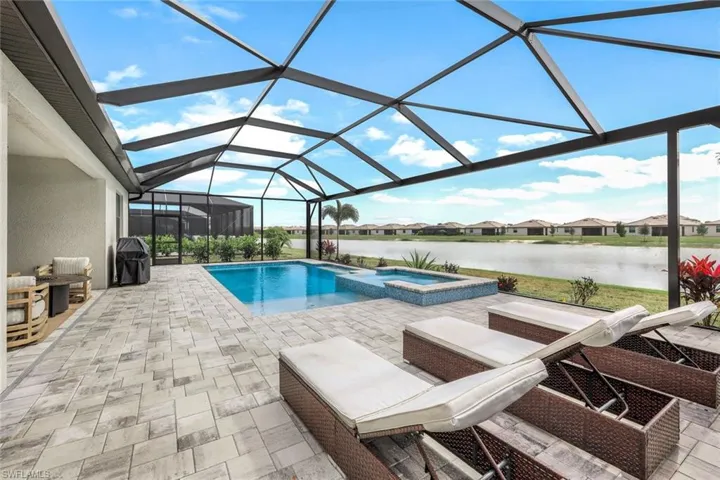 View of swimming pool with an in ground hot tub, a water view, a patio