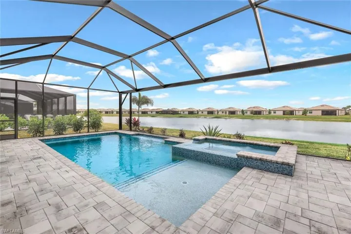 View of swimming pool featuring a water view, an in ground hot tub, a lanai, and a patio area