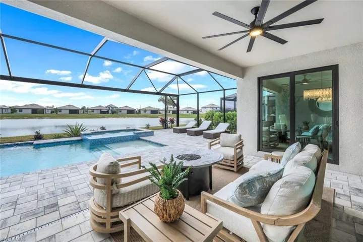 View of patio / terrace with an outdoor living space, a water view, full lanai enclosure, and a pool with hot tub