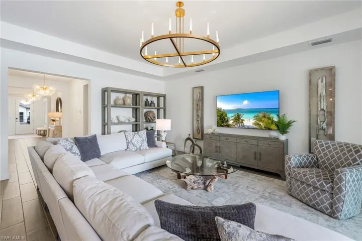 Living room with a notable chandelier and a tray ceiling