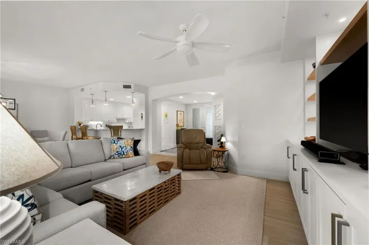Living space featuring recessed lighting, a ceiling fan, a built-in media console with shelving, and wood-finish flooring