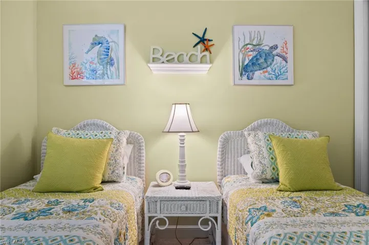 Two individual beds featuring wicker headboards, a central wicker nightstand, and a table lamp