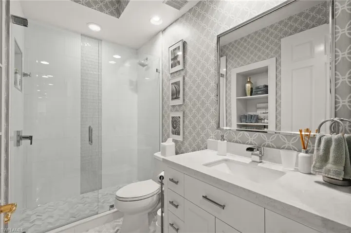Glass-enclosed shower with a chevron-patterned floor and vertical tile accent