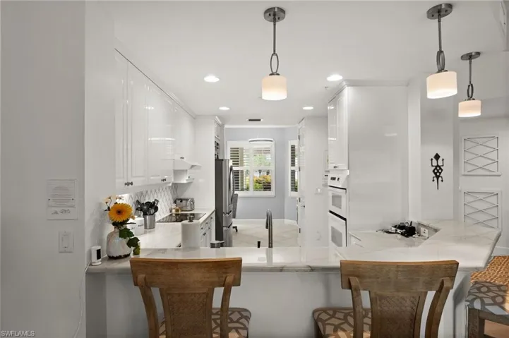 Kitchen featuring white cabinetry, light-toned countertops, recessed lighting, and pendant fixtures