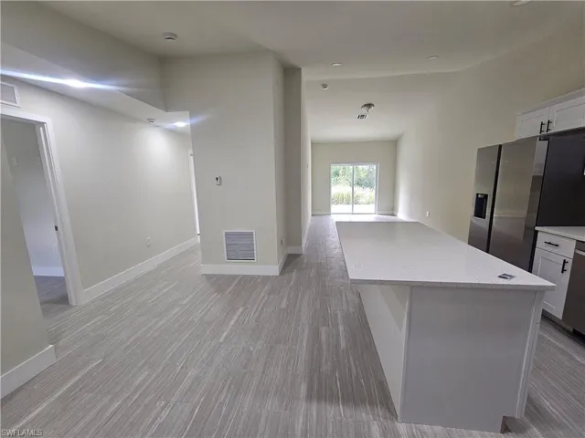 Kitchen featuring white cabinets, stainless steel appliances, light stone counters, and open floor plan