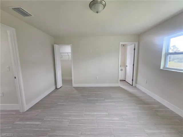 Unfurnished bedroom with a walk in closet and baseboards
