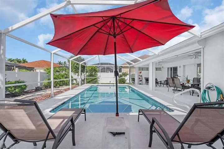 Outdoor pool with a patio, glass enclosure, and a ceiling fan