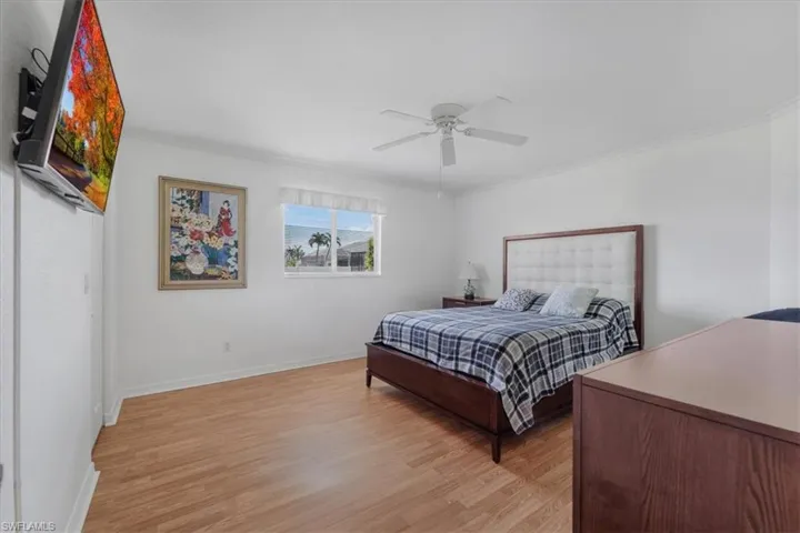 Bedroom with light wood-type flooring, crown molding, and a ceiling fan