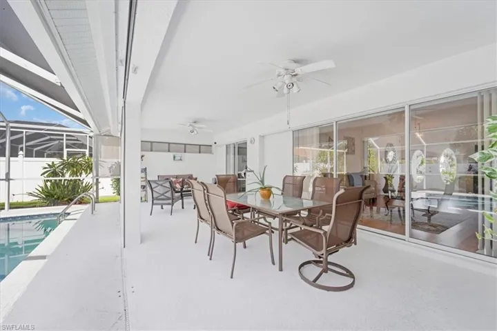 Sunroom with a ceiling fan, outdoor dining area, and a pool