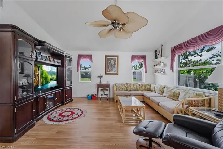 Living room featuring light wood-type flooring, ceiling fan, and lofted ceiling