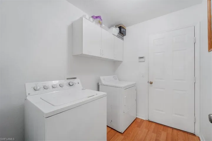 Washroom with washing machine and dryer, cabinet space, and light wood-style flooring